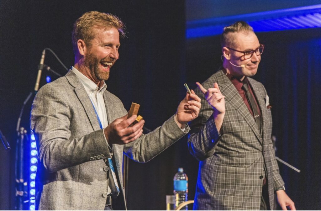 Brendan Dooley performing on stage with an audience member at a corporate event in New Zealand